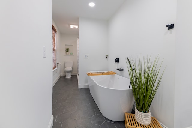 bathroom with a bathing tub, tile patterned flooring, and toilet