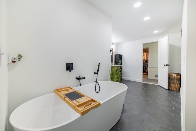 bathroom with a tub to relax in and tile patterned floors