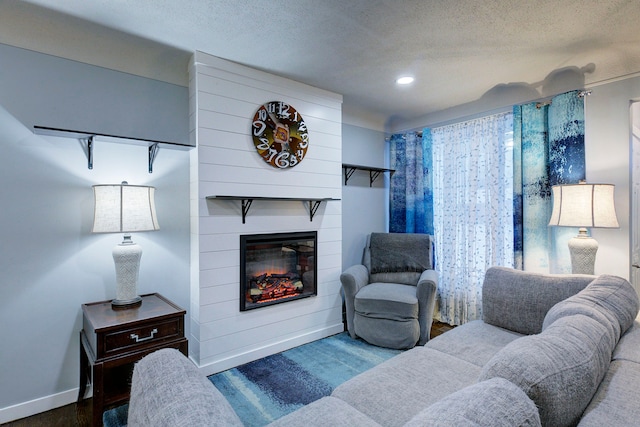 living room featuring a large fireplace, hardwood / wood-style floors, and a textured ceiling