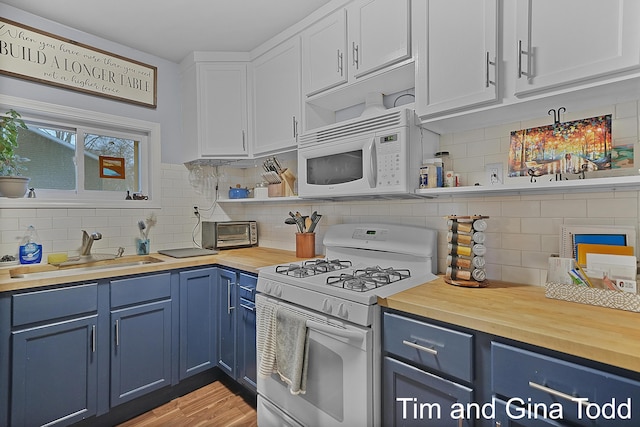 kitchen featuring tasteful backsplash, white appliances, blue cabinets, sink, and white cabinets