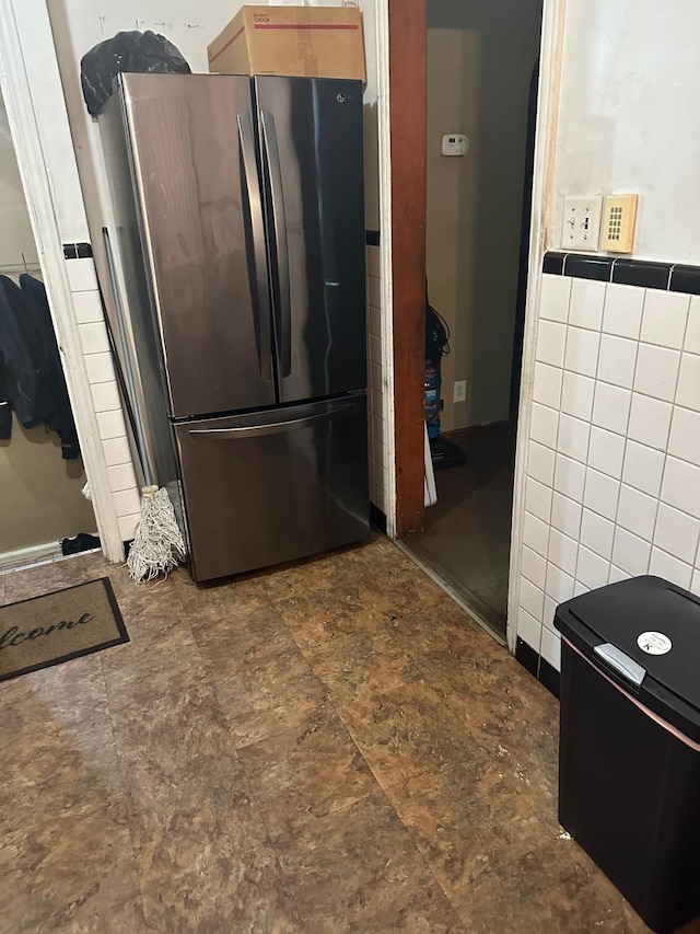 kitchen featuring tile walls and stainless steel fridge