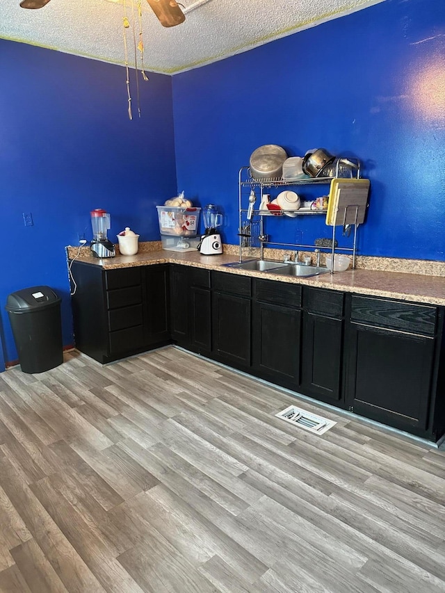 bar featuring ceiling fan, light wood-style flooring, a textured ceiling, and visible vents
