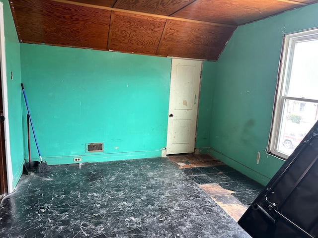 empty room featuring visible vents, baseboards, and lofted ceiling