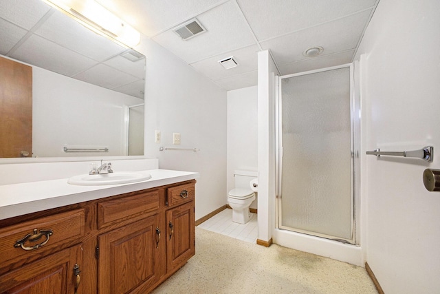 bathroom featuring toilet, an enclosed shower, a drop ceiling, and vanity