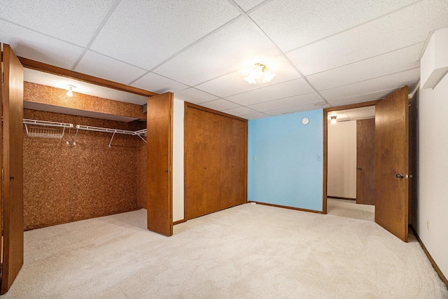 unfurnished bedroom with a paneled ceiling and light carpet