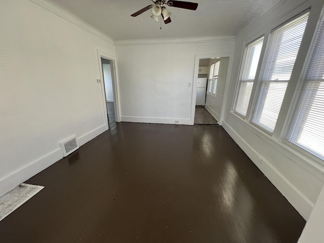 empty room featuring plenty of natural light, crown molding, and dark wood-type flooring