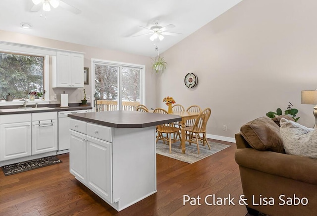 kitchen featuring white dishwasher, a center island, white cabinetry, and sink