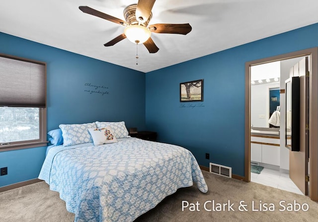 bedroom featuring ceiling fan, light colored carpet, and connected bathroom