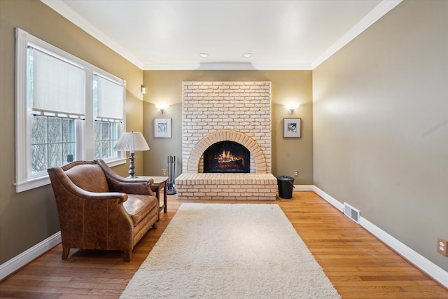 living room with a brick fireplace, hardwood / wood-style floors, and crown molding