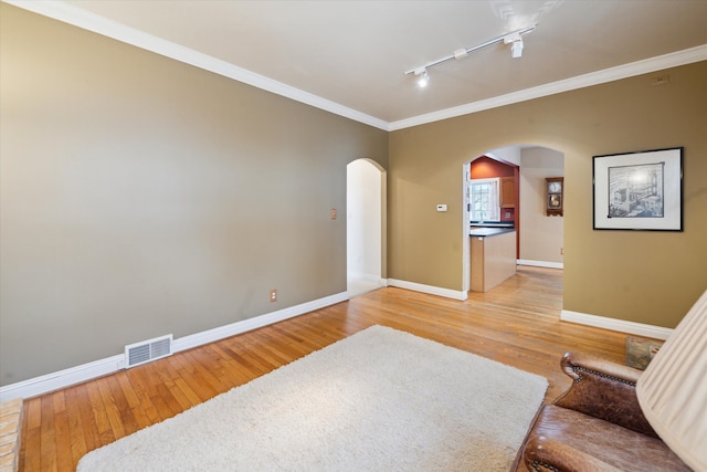 living area featuring light hardwood / wood-style floors, ornamental molding, and rail lighting