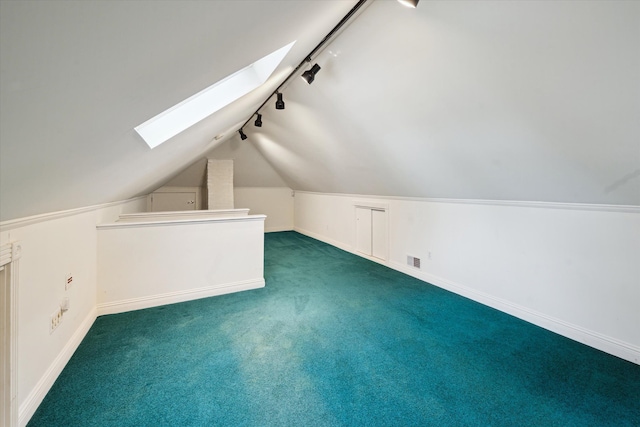 additional living space featuring lofted ceiling with skylight and dark carpet