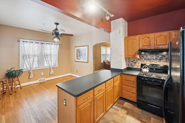 kitchen featuring black appliances, light hardwood / wood-style flooring, decorative backsplash, and kitchen peninsula