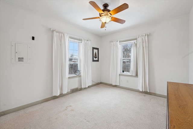 carpeted spare room featuring ceiling fan, a healthy amount of sunlight, and electric panel