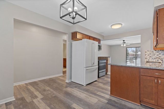 kitchen featuring decorative backsplash, stove, light stone counters, decorative light fixtures, and white fridge