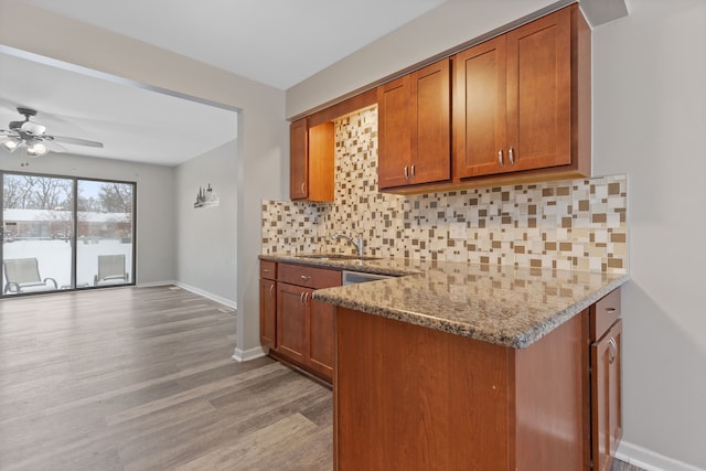 kitchen featuring ceiling fan, sink, light stone counters, light hardwood / wood-style flooring, and decorative backsplash