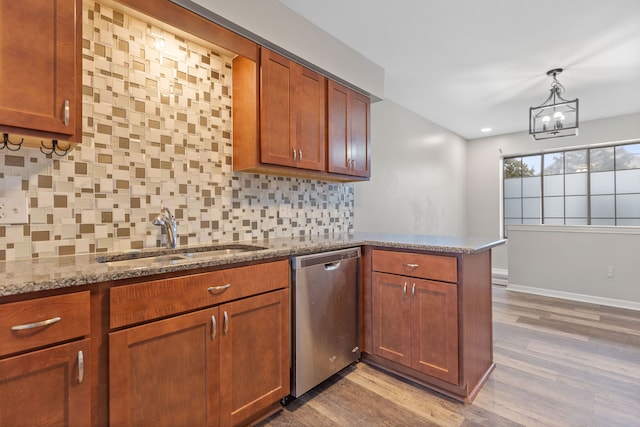 kitchen featuring pendant lighting, dishwasher, an inviting chandelier, sink, and tasteful backsplash