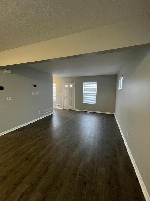 unfurnished living room featuring dark wood-type flooring and a textured ceiling