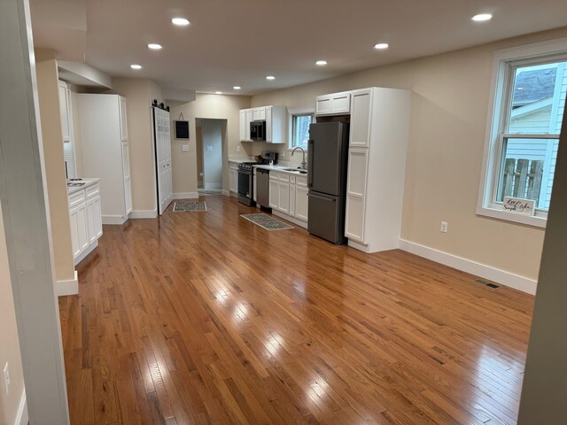 kitchen with stainless steel appliances, white cabinets, light wood-type flooring, and sink