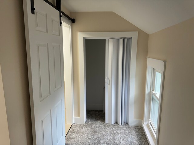 hall featuring light carpet, vaulted ceiling, and a barn door