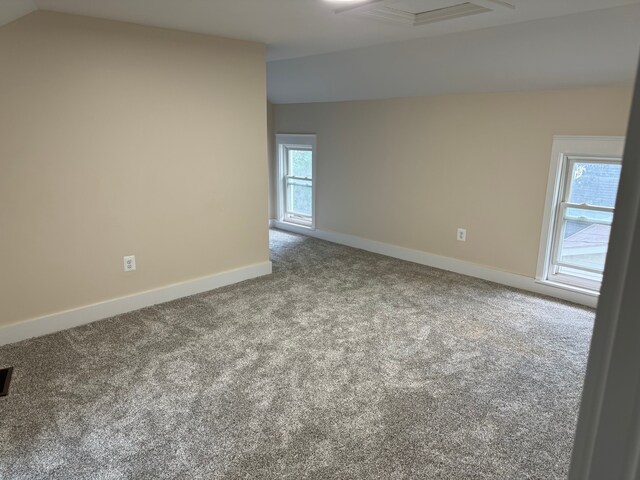 carpeted empty room with lofted ceiling