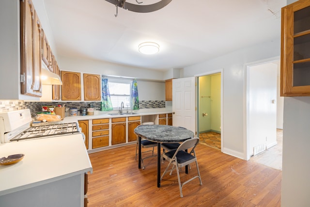 kitchen featuring white range with gas cooktop, sink, decorative backsplash, and light hardwood / wood-style floors