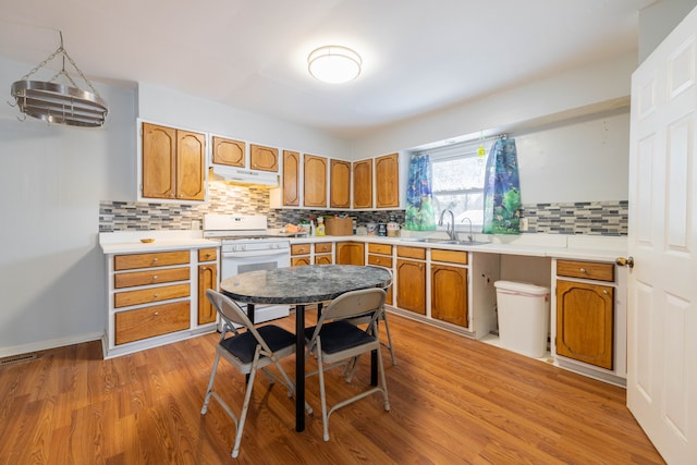 kitchen featuring sink, decorative backsplash, gas range gas stove, and light wood-type flooring