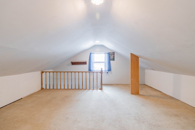 bonus room with light colored carpet and vaulted ceiling