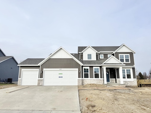 view of front of home featuring roof with shingles, concrete driveway, board and batten siding, a garage, and stone siding