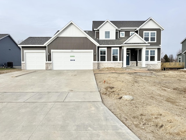 view of front of property featuring roof with shingles, an attached garage, board and batten siding, stone siding, and driveway