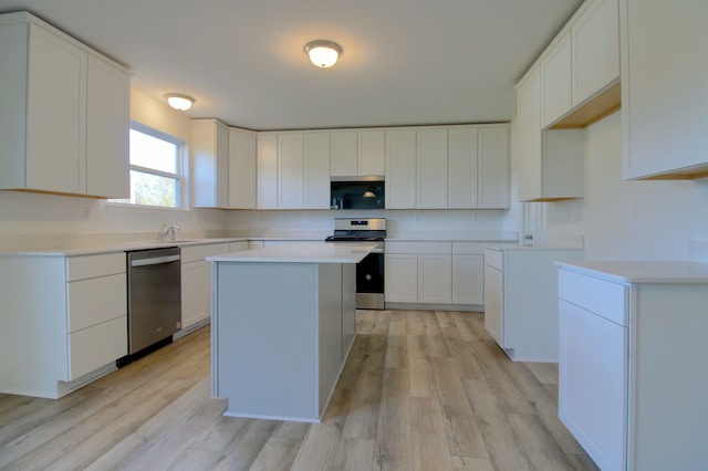 kitchen with appliances with stainless steel finishes, a center island, light wood-type flooring, and white cabinets