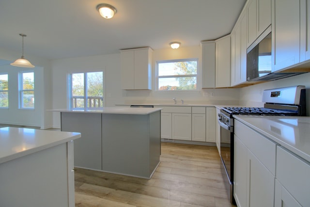 kitchen featuring hanging light fixtures, white cabinetry, a kitchen island, and appliances with stainless steel finishes