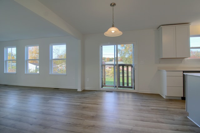 unfurnished dining area with beamed ceiling and light wood-type flooring