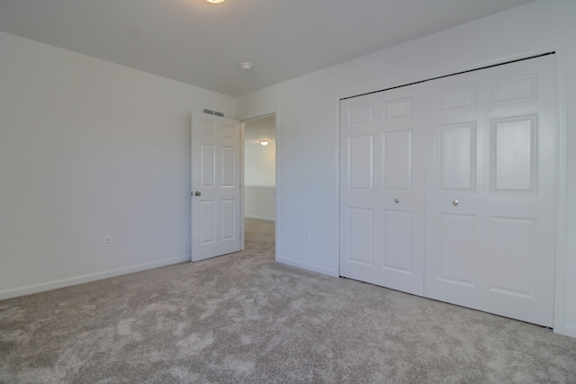 unfurnished bedroom with a closet and light carpet