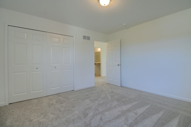 unfurnished bedroom featuring a closet and light carpet