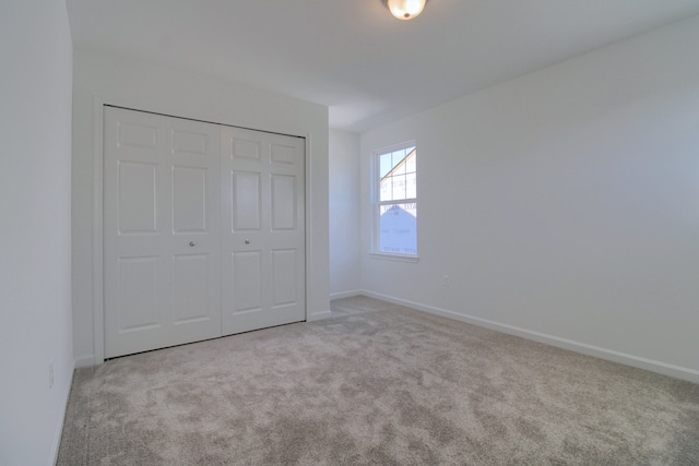 unfurnished bedroom with light carpet and a closet