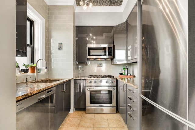 kitchen featuring stone counters, appliances with stainless steel finishes, sink, and decorative backsplash