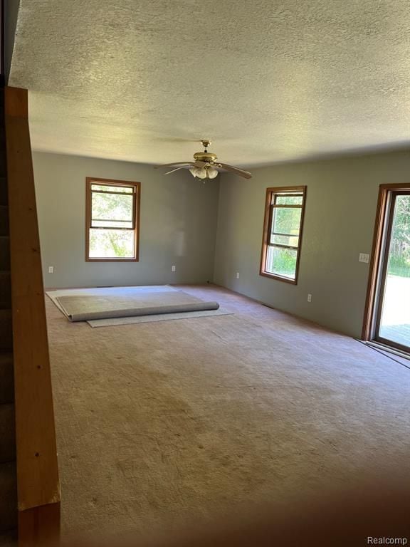 carpeted spare room featuring a textured ceiling and ceiling fan