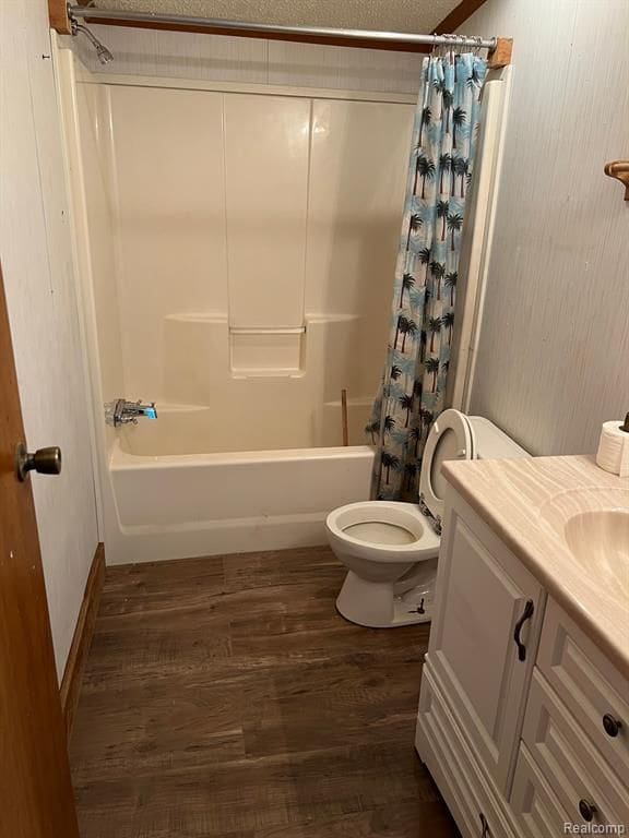 full bathroom with shower / bathtub combination with curtain, toilet, wood-type flooring, vanity, and a textured ceiling