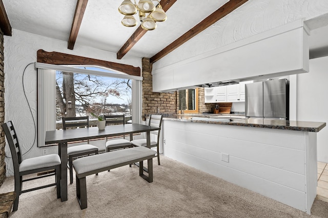 carpeted dining space featuring beam ceiling and an inviting chandelier