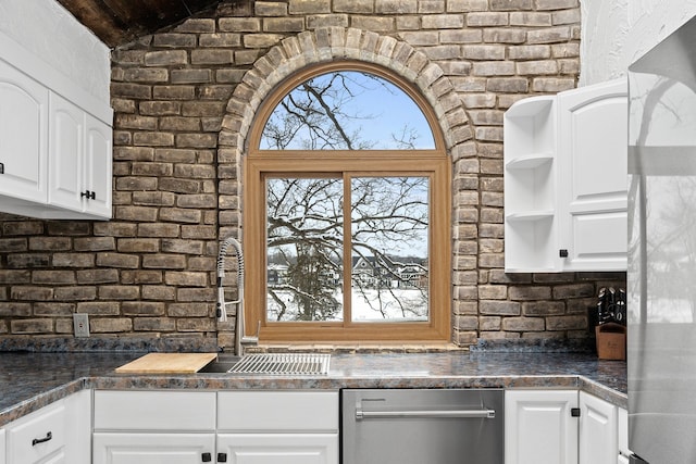 kitchen featuring sink, white cabinets, brick wall, and plenty of natural light