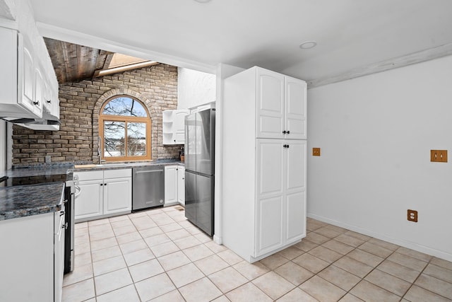 kitchen featuring light tile patterned flooring, white cabinetry, stainless steel appliances, and vaulted ceiling