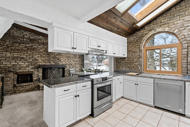 kitchen with kitchen peninsula, white cabinetry, vaulted ceiling with skylight, and appliances with stainless steel finishes