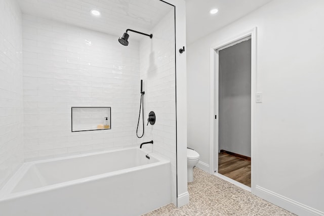 bathroom with tiled shower / bath combo and toilet