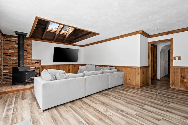 living room featuring a textured ceiling, a skylight, light hardwood / wood-style flooring, and ornamental molding