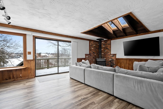 living room featuring a wood stove, a skylight, and wood-type flooring