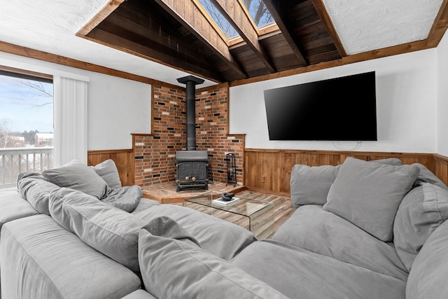 living room with hardwood / wood-style floors, lofted ceiling with skylight, a wood stove, and wood ceiling