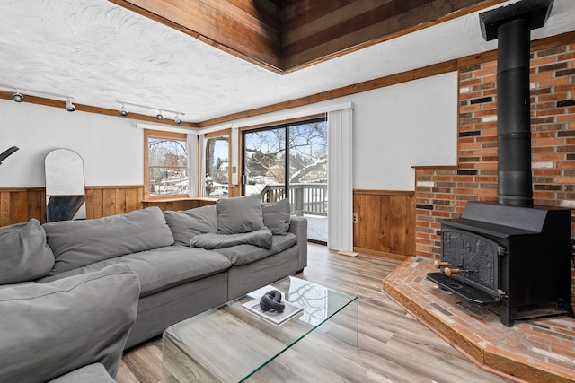 living room featuring light wood-type flooring, a textured ceiling, rail lighting, and a wood stove