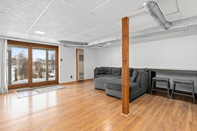 living room with a drop ceiling and light hardwood / wood-style flooring