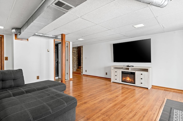 living room featuring light wood-type flooring and a drop ceiling