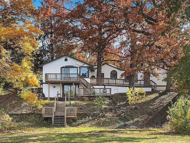 rear view of house featuring a wooden deck and a yard